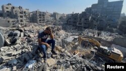 Un bărbat stă pe dărâmături în timp ce palestinienii caută victime la o zi după loviturile israeliene asupra caselor din tabăra de refugiați Jabalia din nordul Fâșiei Gaza, 1 noiembrie 2023.