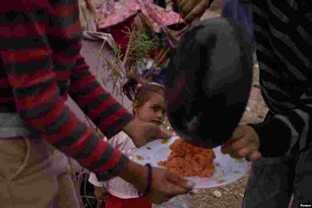 Susej, një vajzë dyvjeçare emigrante nga Venezuela, shikon vezët që familja e saj përgatit për darkën e tyre teksa ata kalojnë netët përgjatë bregut të lumit Rio Grande ndërsa presin t'u dorëzohen autoriteteve të imigracionit në El Paso, Teksas, Shtetet e Bashkuara të Amerikës, 23 mars 2024.