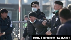 Орусиянын полициясы миграциялык борбордон чет элдик жаранды кармап баратат. 