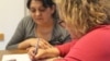 Rozina, o romă din regiunea Transcarpatia din Ucraina, învață să scrie cu ajutorul lui Agnes Pletser de la ONG-ul Taleta.