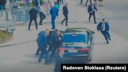 A merénylet utáni pillanatok a Reuters fotóján, ahogy a testőrök autóba segítik a sérült Robert Ficót Nyitrabányán 2024. május 15-én