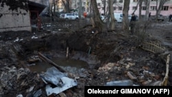 Чоловік стоїть біля вирви у дворі житлового будинку, пошкодженого внаслідок атаки безпілотника в Одесі 17 січня 2024 року
