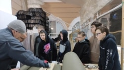 Nxënësit rusë duke mësuar se si të presin pëlhura me një makinë, në mënyrë që të bëjnë rrjeta kamuflazhi për ushtrinë ruse.