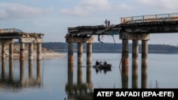 Civili traversând râul Siverski Doneț cu barca pe sub un pod avariat în orașul eliberat Stari Saltiv, la est de Harkov.(foto de arhivă)