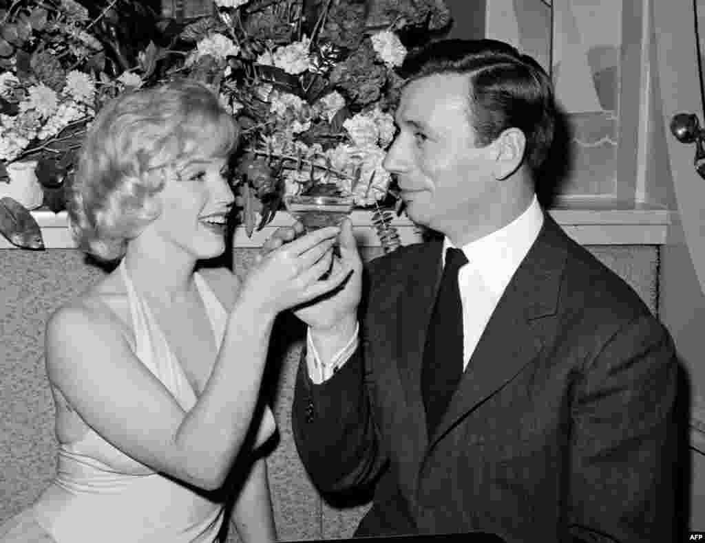 Monro ndan një gotë shampanjë me aktorin dhe këngëtarin francez Yves Montand në Holivud, pas shfaqjes së filmit të tyre "Let's Make Love" me regji të Xhorxh Cukor, në vitin 1960.