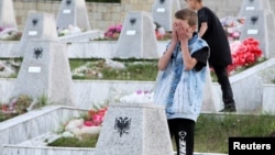 Një djalosh duke u lutur para varrezave të personave të vrarë në Reçak më 1999.