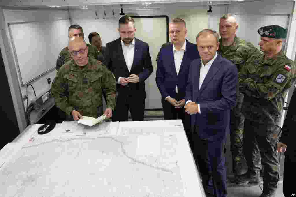 Kryeministri i Polonisë, Donald Tusk, (përpara djathtas), ministri i Mbrojtjes, Wladyslaw Kosiniak-Kamysz (në mes) dhe ministri i Brendshëm, Tomasz Siemoniak, (në mes ana e djathtë) duke vizituar trupat në Dubicze Cerkiewna, në lindje të Polonisë, më 29 maj. "Ne nuk kemi të bëjmë me asnjë azilkërkues këtu, kemi të bëjmë me një operacion të koordinuar, shumë efikas -- në shumë nivele -- për ta thyer kufirin polak dhe me përpjekje për të destabilizuar vendin", tha Tusk. 