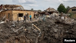 Люди стоять біля зруйнованих житлових будинків на місці російського ракетного удару у місті Покровськ Донецької області. 24 червня 2024 року