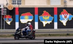 Dy persona shihen në një motoçikletë, e cila ka mbrapa hartat e Kosovës, Maqedonisë së Veriut, Bosnje-Hercegovinës dhe Malit të Zi, me flamuj të Serbisë në to. Beograd, gusht 2021.