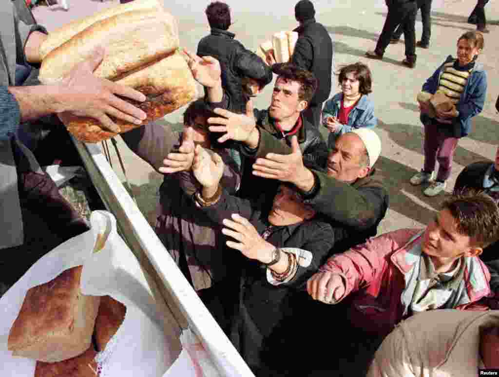 Refugjatë shqiptarë nga Kosova, duke marrë bukë në Kukës pasi kanë ikur nga luftimet që po zhvilloheshin në vendbanimet e tyre, 30 mars 1999. Arben Celi/Reuters. 
