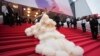 Cunoscut publicului larg pentru vedetele defilând pe covor roșu și petrecând pe iahturi, festivalul de film de la Cannes este și un mare târg (în imagine, actrița chineză Wan QianHui, pozând la ceremonia de deschidere a celei de-a 78-a ediții a festivalului, pe 13 mai 2025)