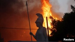 Статуата на божицата Атена во селото Варибоби, 30 километри северозападно од Атина кое што е зафатено од пожар, 03.08.2021