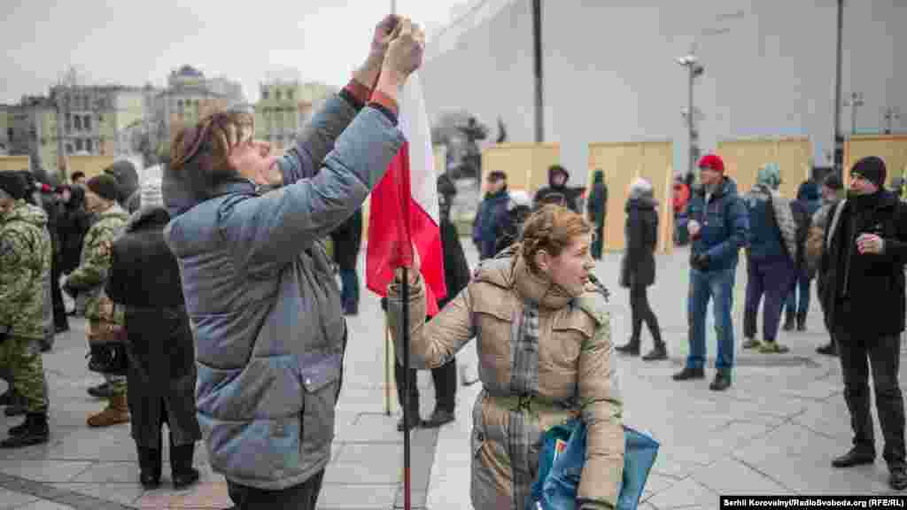 Люди чіпляють українську стрічку на польський прапор
