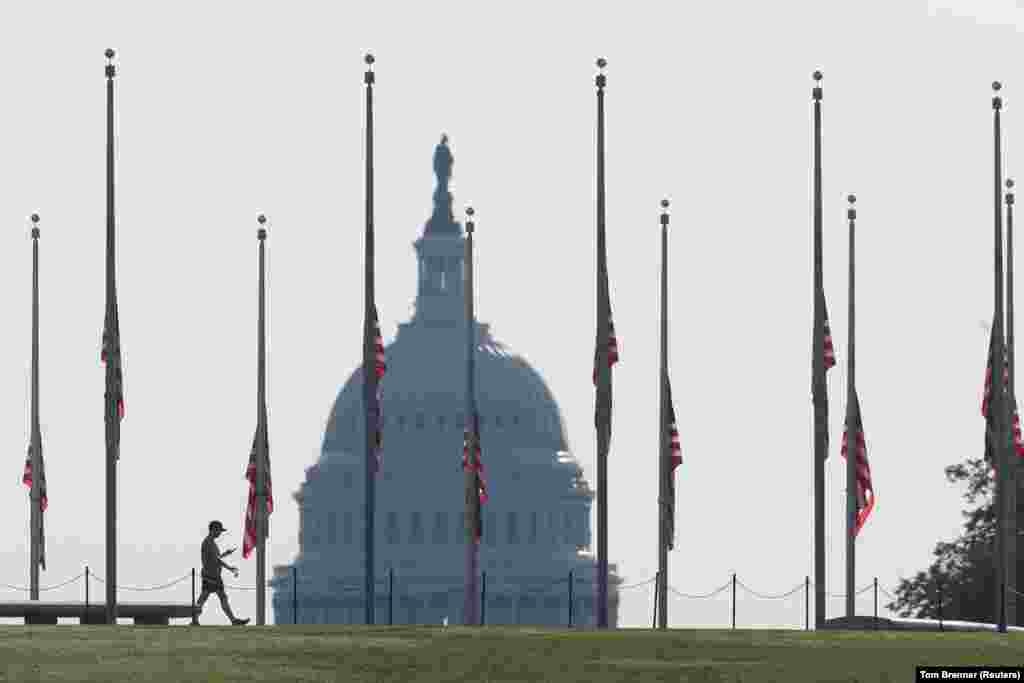 Një vizitor ecën pranë Monumentit të Uashingtonit teksa flamujt amerikanë janë ulur në gjysmështizë për të nderuar viktimat e 11 shtatorit. Uashington DC, 11 shtator, 2021. 