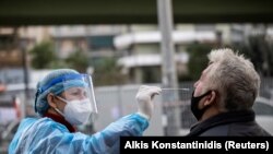 Здравствен работник зема брис од маж за брз тест во Атина, Грција, 18 декември 2020 година