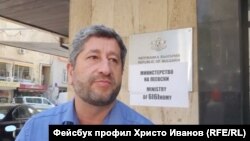 Христо Иванов пред министерството на икономиката. Зад гърба му се вижда надписът Министерство на Пеевски" и "Ministry of 6I6Inomy"