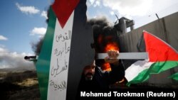 WEST BANK -- A demonstrator carries a model of a map with the colors of the Palestinian flag reading "Jerusalem is the eternal capital of Palestine" during a protest against the U.S. President Donald Trump's Middle East peace plan, in the village of Bili