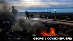 МАКЕДОНИЈА -- Луѓе кои собираат пластични шишиња на депонија поминуваат покрај отворен оган пред најголемата термоцентрала „РЕК БИТОЛА“ во близина на градот Битола. 