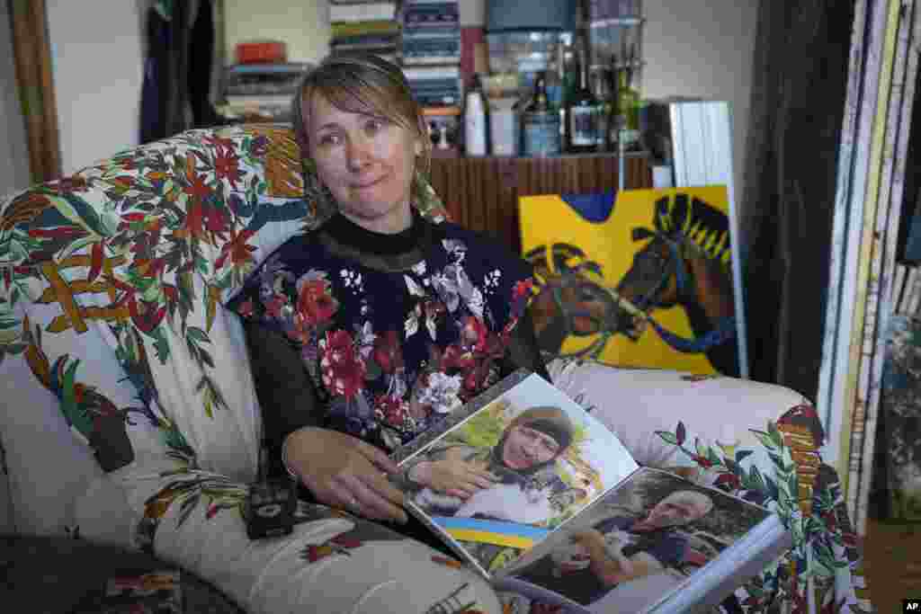 Iulia Movchan, soția unui soldat ucrainean ucis în luptă, arată fotografii cu soțul ei. Femeile de la studio fac parte dintr-un proiect de terapie prin artă, numit „În viață. Adevărate povești de iubire”, care încearcă să onoreze amintirea celor care au murit, ajutând în același timp femeile să facă față pierderii suferite. Proiectul de artă este gratuit, iar artiștii locali își oferă voluntar timpul pentru a ajuta femeile să își exprime durerile pe pânză.