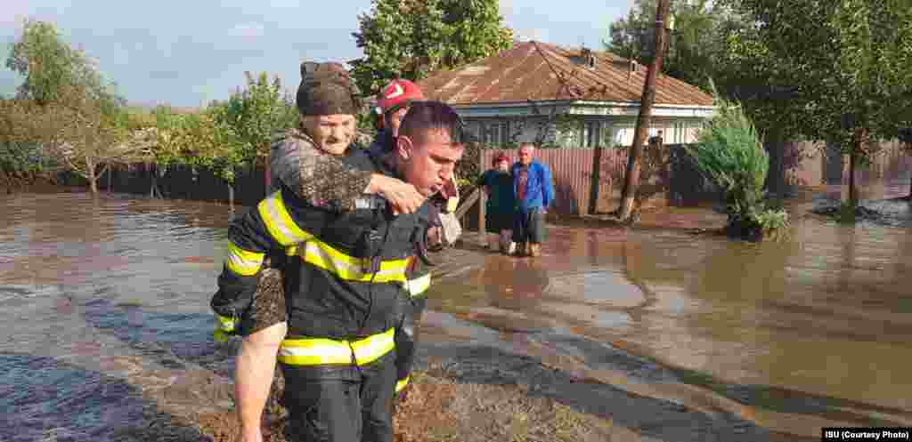 O vârstnică este cărată în spate de un pompier. Localitatea Cudalbi/jud. Galați. 