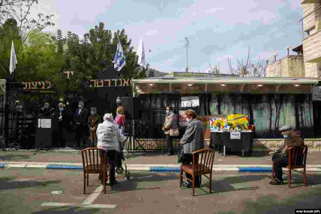 Supraviețuitori ai Holocaustului poartă mască și păstrează distanța fizică în timpul participării la ceremonia dedicată Zilei internaționale a comemorării Holocaustului din orașul Haifa, din nordul Israelului. Evenimentul a avut loc în aer liber din cauza pandemiei de COVID-19 și a faptului că țara se află în carantină. 27 ianuarie, 2021. 